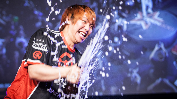 Hyun wearing his black and orange jersey grins while spraying champagne on the main stage at DreamHack.