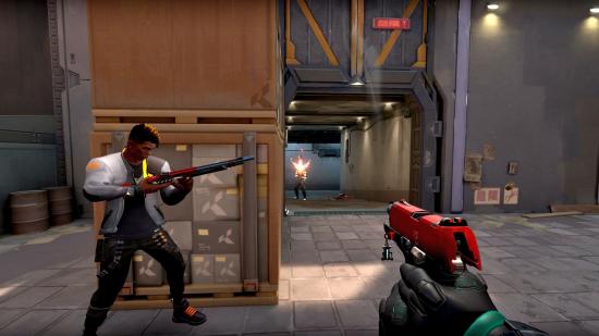 A Valorant character reloads a shotgun while standing behind a stack of large crates, as the player fires a red-accented pistol at an enemy positioned down a hallway.