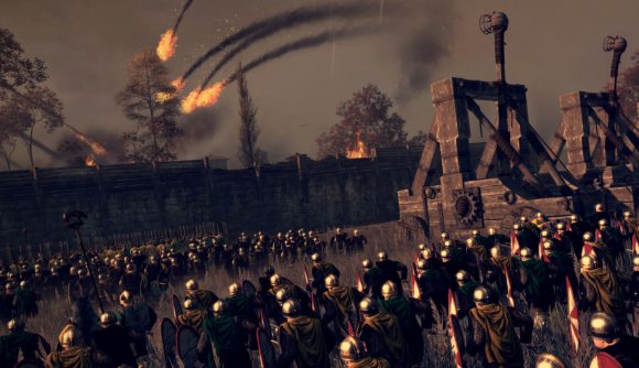 An army laying siege to a town. Several catapults have just fired flaming ammunition. Some troops are gathered outside the wall.