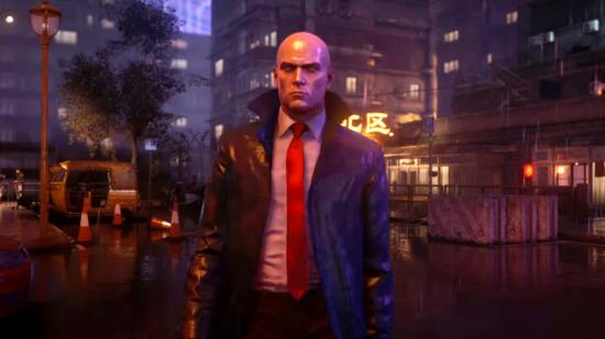 Hitman freelance mode: Agent 47 stands in the rain at night on a neon-lit Chongqing street
