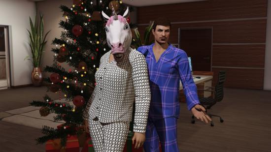 Best Christmas games - a couple in pyjamas standing in an office with a giant Christmas tree. The woman in the light PJs is also wearing a unicorn mask.