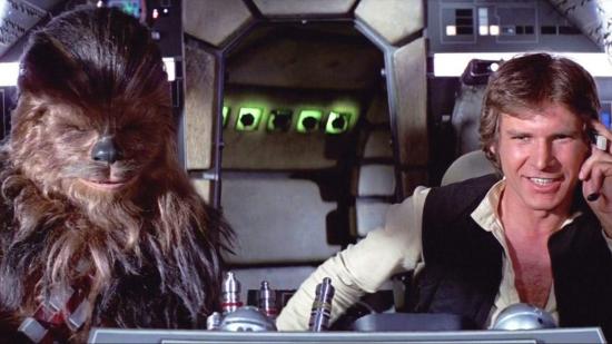 Han Solo and Chewbacca sitting in the bridge of the Millenium Falcon, Han is smiling
