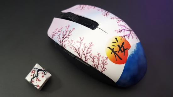 A Razer Orochi V2 gaming mouse with a custom shell on top featuring a sunset over Mount Fuji and blossom along the clickers