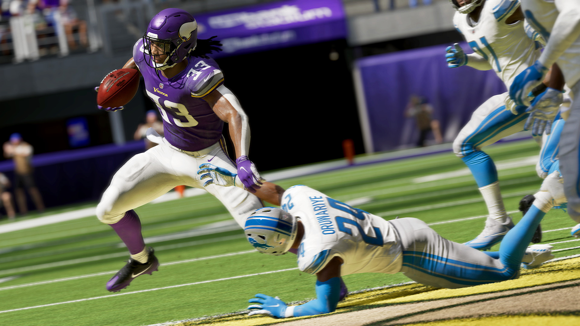 A man in a purple jersey running past a man on the floor in Madden 21