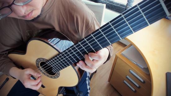 Cecil Chau, aka GuitarSVD, plays an arrangement on his classical nylon-string guitar at his desk.