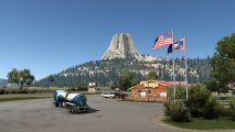 A number of vehicles parked outside a Wyoming gift shop near a mountain in the new American Truck Simulator DLC