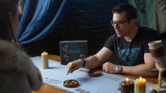 Two people sit at a table to play Orlog by candlelight