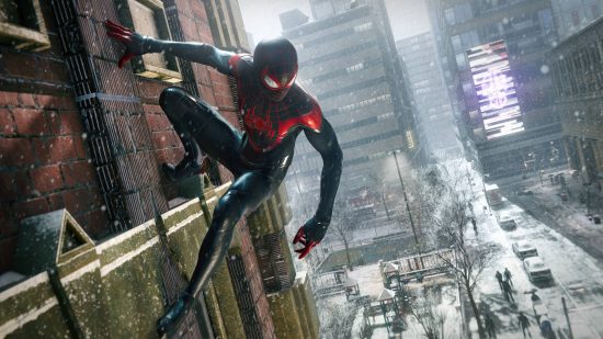 Best Christmas games - Spider-Man is hanging from the side of a building in Spider-Man Miles Morales. The street below is bustling with activity, despite the snow.