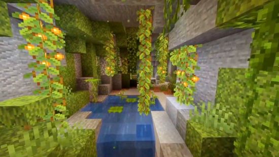 Minecraft lush caves: Lots of glow berries light the way through a cave, which features small pools of water, clay, and drip leaves.