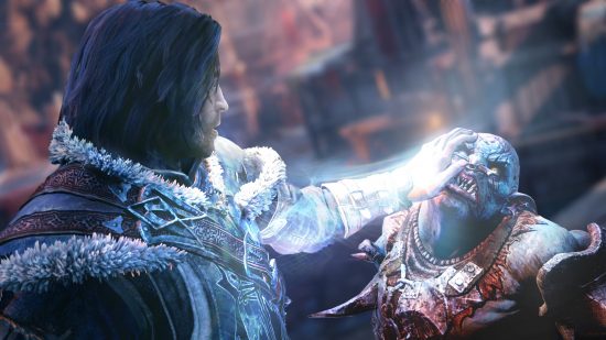 Best action-adventure games - a man places his hand on an orc's face in Middle-earth: Shadow of Mordor.