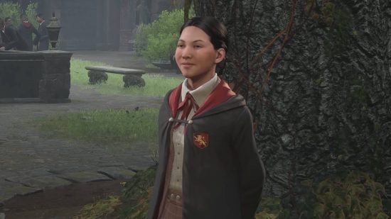 Hogwarts Legacy -karaktärer - Nellie Oggspire står bredvid ett träd. Hon är en Gryffindor -student