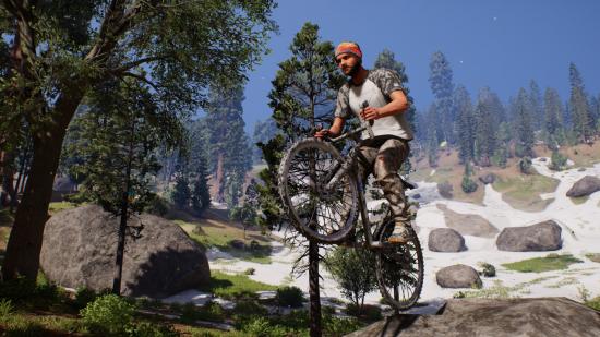 A man on a mountain bike pulls a wheelie on top of a boulder in Riders Republic.