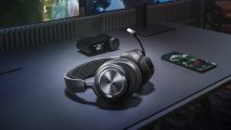 The SteelSeries Arctis Nova Pro Wireless sits on a desk next to its dock, a monitor, and a mobile phone