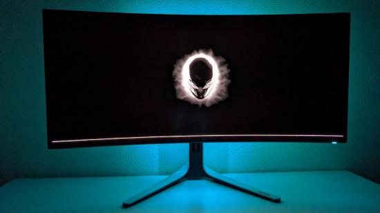 The Alienware AW3423DW gaming monitor, in a dark room with its blue AlienFX lighting activated