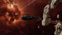 A thrasher crosses a large asteroid with an orange nebula's cloud covering the background, and a blue laser beam streaks by in Eve Online
