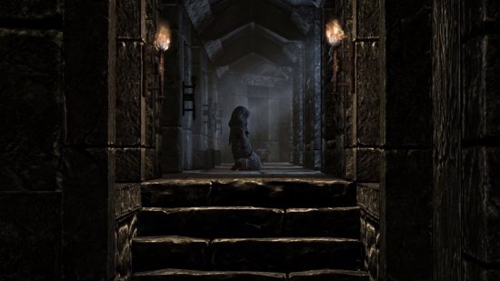 Skyrim Console Commands and Cheats: Une figure à capuche s'agenouille au milieu d'un couloir en pierre, des torches et du clair de lune fournissant la seule source de lumière