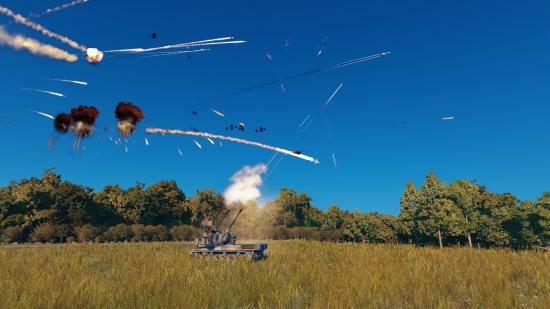 A self-propelled anti-aircraft artillery vehicle fires at fighter jets from a grassy field surrounded by green trees in Warno