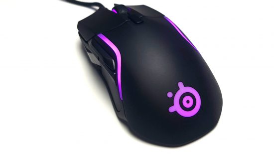 El mejor mouse para juegos, el SteelSeries Rival 5, brilla con una luz púrpura contra su carcasa negra y un fondo blanco.