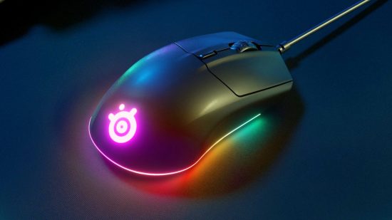 El mejor mouse para juegos en un presupuesto, el SteelSeries Rival 3, brilla con su luz de arcoíris en un escritorio oscuro