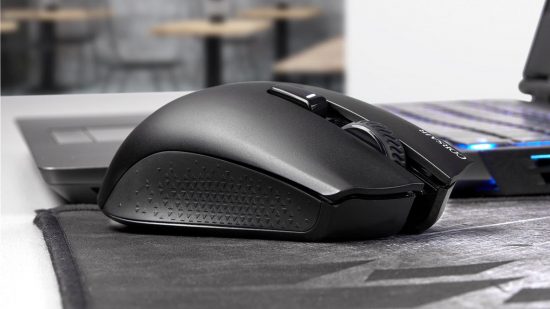 The best cheap wireless gaming mouse, the Corsair Harpoon RGB wireless, is on a Corsair mouse mat, next to a gaming laptop