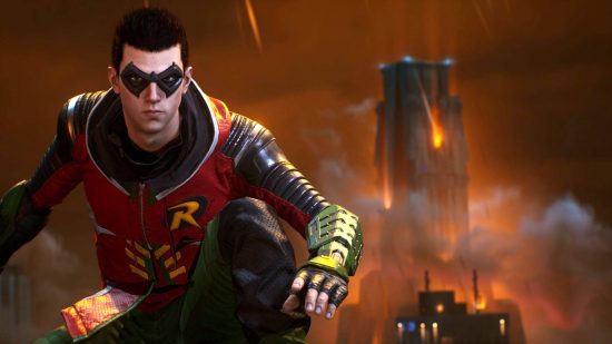 Gotham Knights styles: Robin standing on a rooftop in a red and green outfit with a hood. Fire is raining down on the buildings behind him.