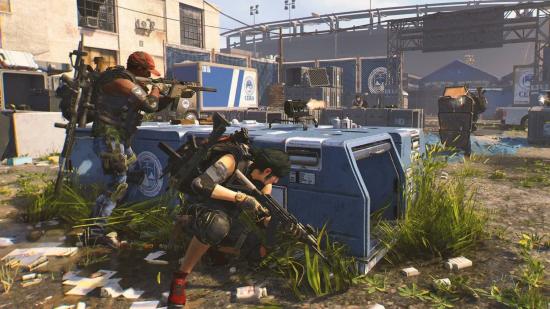 The Division 2 Fairview Crew apparel event delayed: Two agents take cover and fire from behind a blue supply container as a shielded enemy approaches.