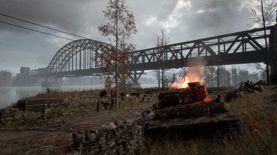 Hell Let Loose Update 12: A burned-out German tank sits in the foreground in front of the Ludendorff Bridge in Remagen, Germany