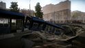 Escape from Tarkov screenshots: A tram has fallen through the street into a sinkhole leading to an underground sewer or culvert; large apartment buildings can be seen in the background