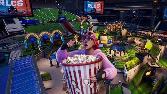 Fortnite and Rocket League are together again. This image shows a Fortnite character eating popcorn in front of a Rocket League stadium built in Fortnite.