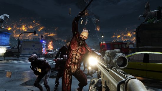 Best zombie games: shooting a zombie with impressive muscles in Killing Floor 2. Smaller zombies are around it and lots of abandoned cars. There is lots of smoke in the air and a radio tower is about to crash down.