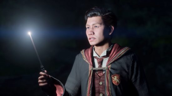 Hogwarts Legacy trailer: a young wizard holding their wand up to help light a dark cave