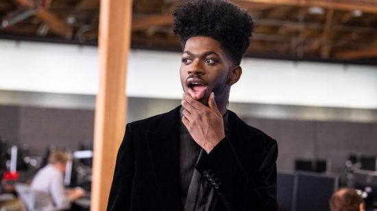 Lil Nas X is performing at League of Legends Worlds: Black rapper in a black suits stands looking confused and sticking out tongue