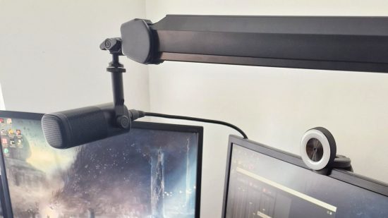 The Elgato Wave DX XLR microphone is suspended above a gaming monitor on an Elgato arm