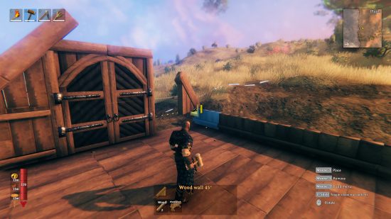 Best building games: A player builds a wooden structure in a meadow in Valheim