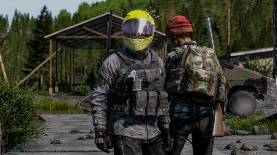 DayZ Update 1.19: A survivor in a visored motorcycle helmet and web gear looks toward the camera as a companion in a red stocking cap heads toward a covered bridge on a mountain road