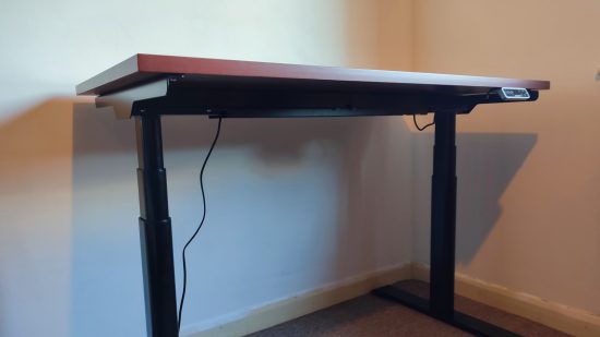 Revisión de Flexispot E8: el escritorio de pie completamente construido se apoya contra una pared blanca