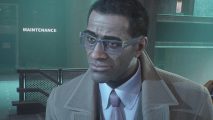 Gotham Knights fast travel: Lucius Fox is standing by a staircase and the maintenance door. He is wearing a trenchcoat, suit, tie, and thick blue glasses.