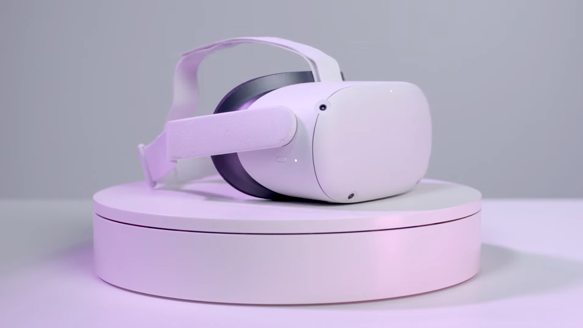 Et Oculus Quest 2 -headset ovenpå en hvid sokkel, badet i lilla farvetone