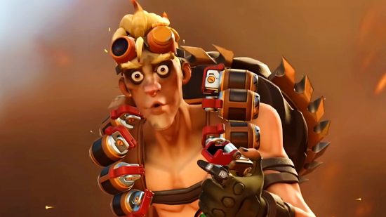 Overwatch 2 phone verification removed - Junkrat makes a shocked face to camera as an explosion goes off behind him