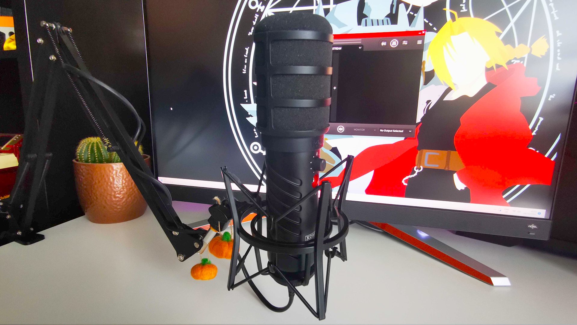 Rode X XDM-100 gaming mic on boom arm with monitor in backdrop