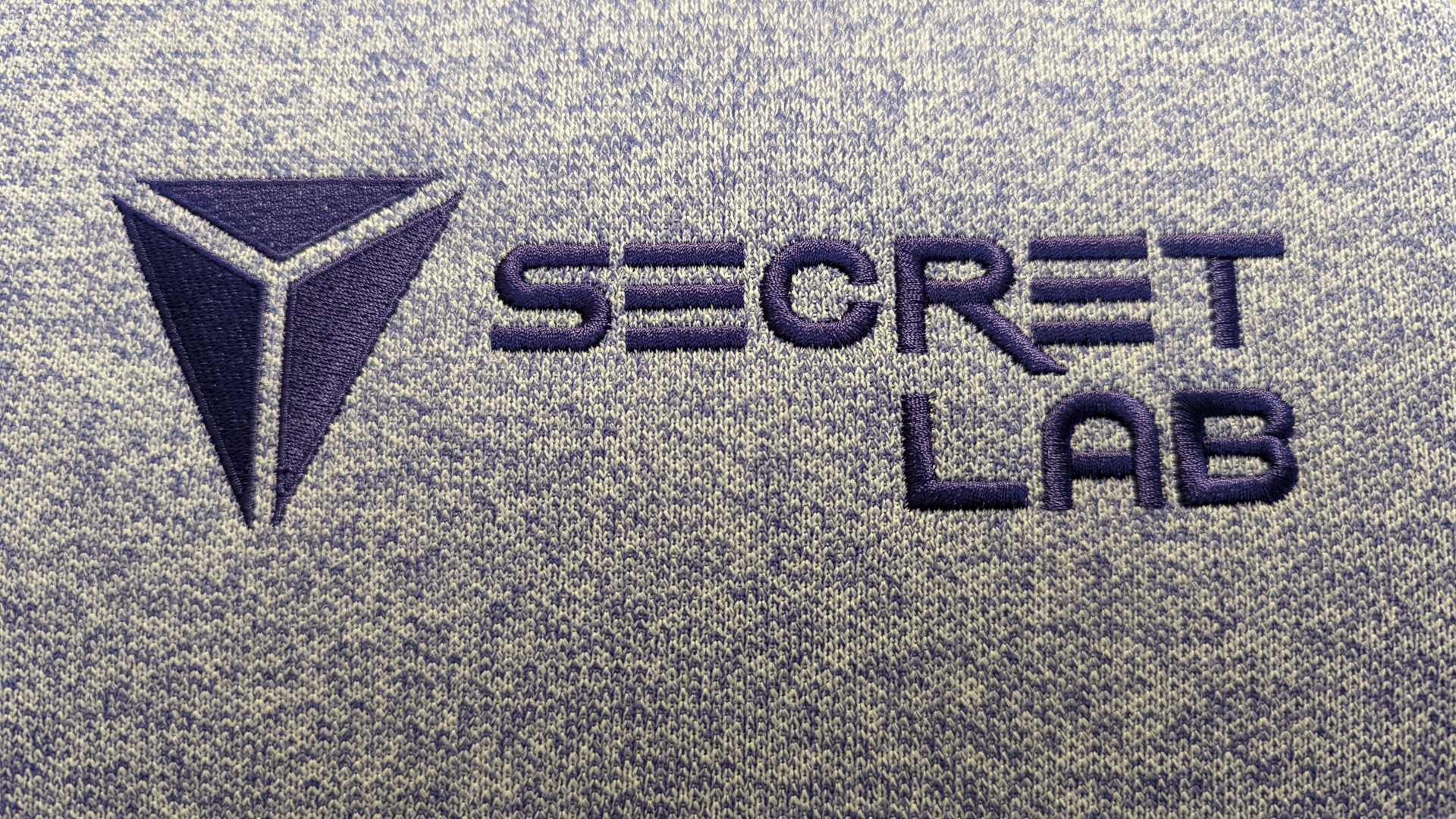 The Secretlab logo, stitched in purple against a lighter tone