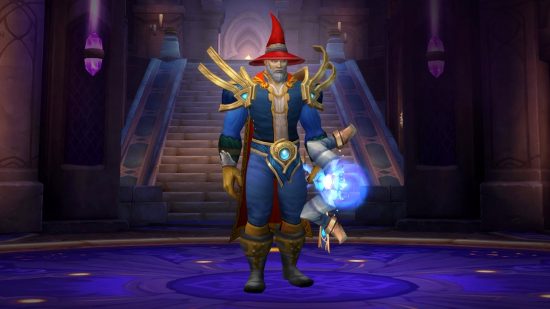 WoW Dragonflight mage tier set: A wizard with a red pointy hat and flowing blue robes stands with a glowing blue crystalline staff