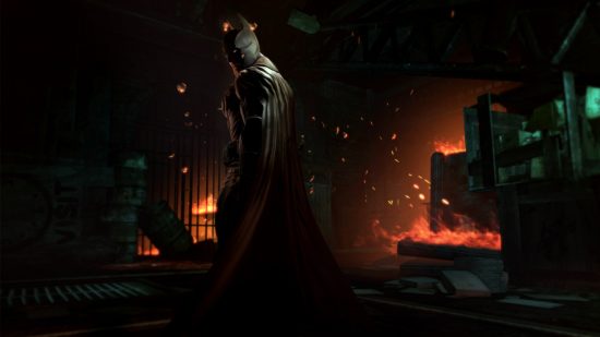 Beste Batman Games - Batman stond tussen enkele brandende kratten in Arkham Origins
