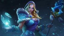 A blond woman wearing a hood with bright blue eyes stares into the camera while summoning frost holding an icy staff