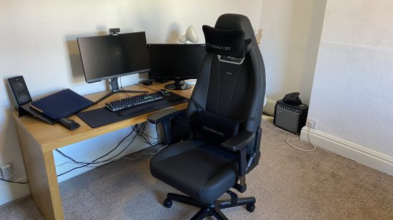 Noblechairs Legend review: an image of the black chair in front of desk that has a computer and screens on it