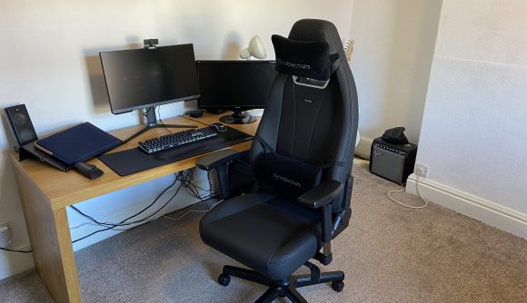 Noblechairs Legend review: an image of the black chair in front of desk that has a computer and screens on it