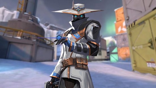 Valorant patch notes: 5.10 update finally buffs Cypher, nerfs Fade: A man wearing a wide brimmed hat and a black mask that only shows glowing blue eyes stands with a small disk in his hand across his chest