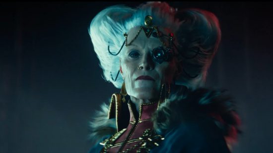Warhammer 40k Darktide Inquisitor: An elderly woman wearing a fur-lined cape, gold brocade, a complex hairstyle, and a mechanical monocle