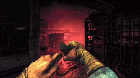Amnesia The Bunker Release Date: Screenshot of a player about to unscrew a grenade and throw it into a gloomy shop room lit up with an eerie red glow