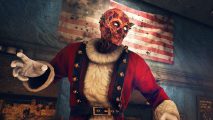 Fallout 76 Holiday event: A Holiday Scorched wearing red Santa outfit with white gloves, white fur trim, and black suspenders with jingle bells attached to it, stands in front of a vintage American flag with faded colours and stars arranged in a circle